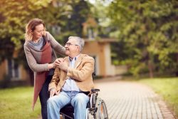 senior man in wheelchair with happy caregiver